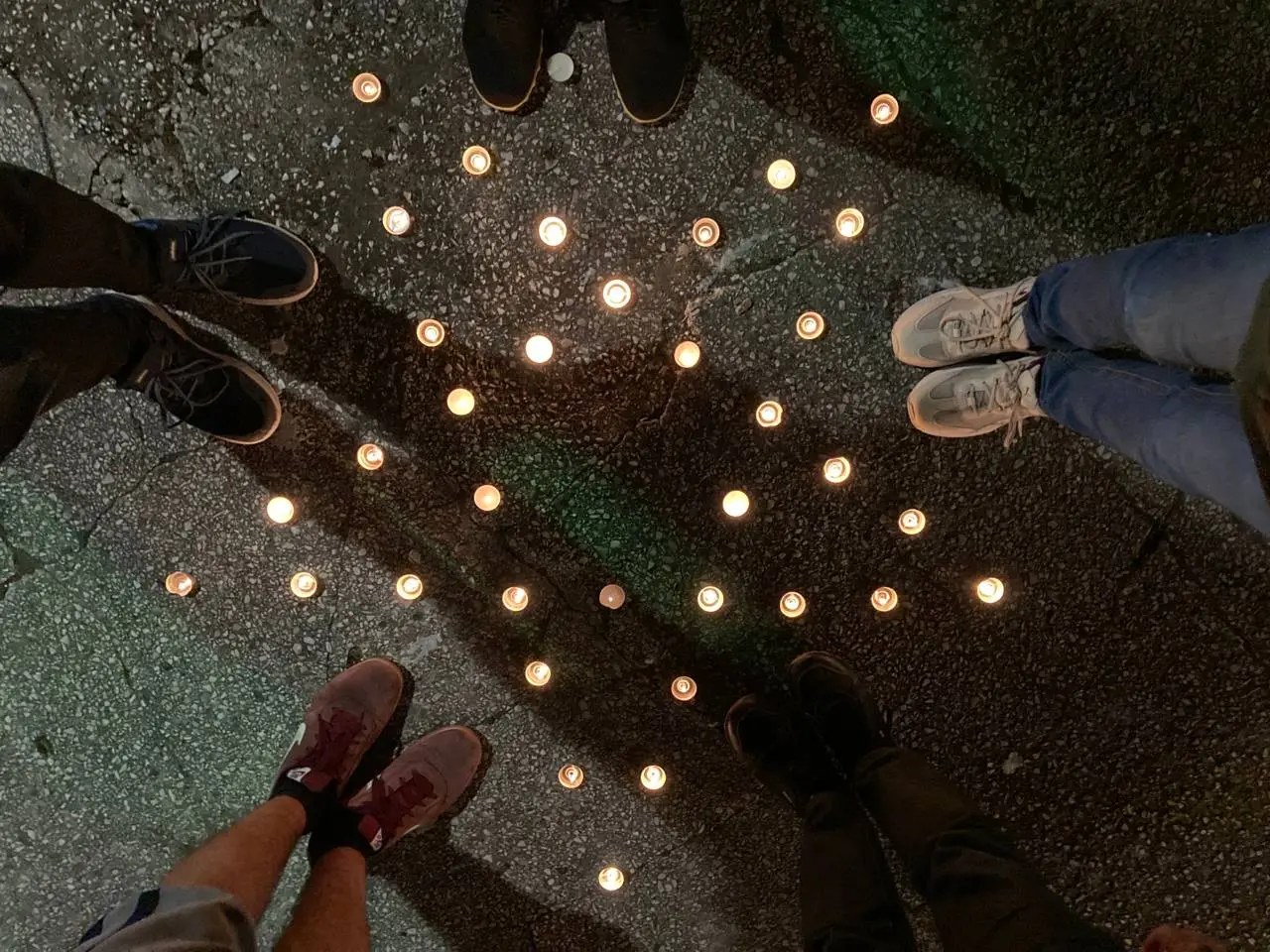 A group of participants standing in a circle around a star assembled in candles
